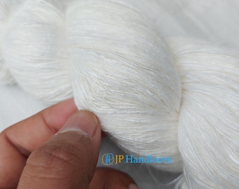 Peut inclure: Une pelote de fil de soie blanc, avec une texture douce et délicate. Le fil est enroulé de manière lâche et semble être filé à la main.