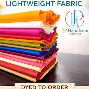 Könnte beinhalten: Ein Stapel farbenfroher Tussar-Seidenstoffe, darunter gerollte und gefaltete Stücke in Gelb, Orange, Pink und Rot. Der Text auf dem Bild lautet "Tussar Silk Lightweight Fabric" und "Dyed to Order". Die Stoffbreite beträgt 112 cm. Das JP Handloom Logo ist ebenfalls zu sehen.
