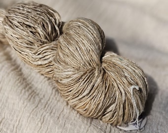 May include: A skein of natural colored yarn made from a blend of linen and silk. The yarn is loosely wound and has a slightly textured appearance.