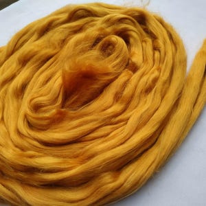 May include: A large bundle of golden yellow wool fiber. The wool is soft and fluffy, and it is perfect for spinning or felting.