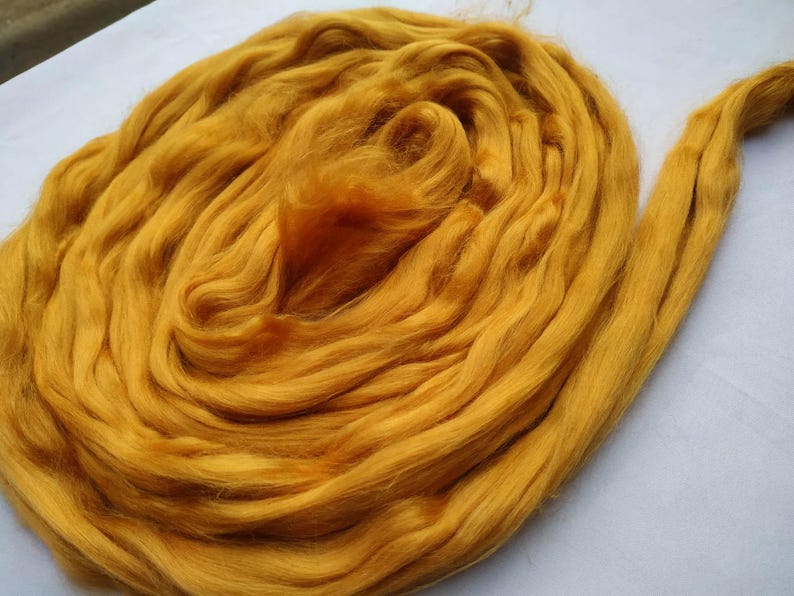 May include: A large bundle of golden yellow wool fiber. The wool is soft and fluffy, and it is perfect for spinning or felting.