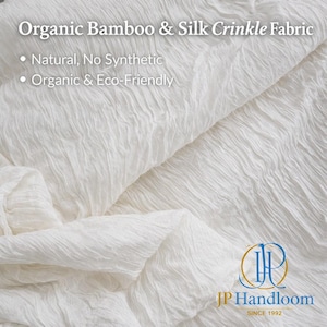 Puede incluir: Primer plano de tela arrugada blanca hecha de bambú y seda orgánicos. La tela tiene un aspecto texturizado y ondulado. El texto de la imagen dice "Organic Bamboo & Silk Crinkle Fabric", "Natural, No Synthetic" y "Organic & Eco-Friendly". El logotipo de JP Handloom está en la parte inferior derecha.