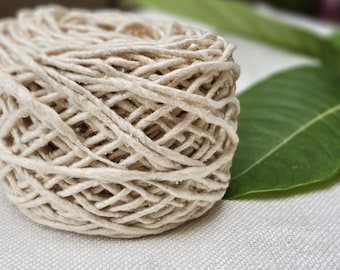 May include: A close-up of a ball of natural fiber twine, wound tightly and ready for crafting projects. The twine is a light beige color and has a slightly rough texture.