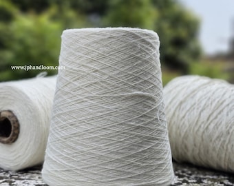 Peut inclure: Trois bobines de fil de coton blanc, enroulées serrées et prêtes à être tricotées ou tissées. Le fil est naturel et non blanchi, avec une surface douce et légèrement texturée.