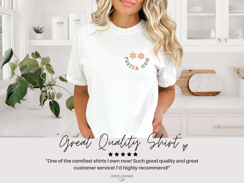 May include: White t-shirt with a colorful graphic that says "Foster Mom" with flowers around the text.