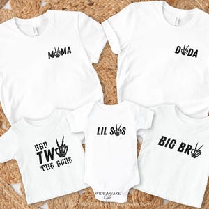 Puede incluir: Un conjunto de cinco camisetas blancas con texto negro y gr&aacute;ficos de signo de paz. Las camisetas dicen "Mama", "Dada", "Lil Sis", "Big Bro" y "Bad Two The Bone".