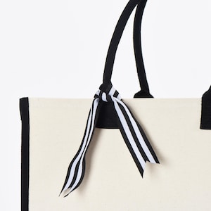 a white bag with a black and white striped bow