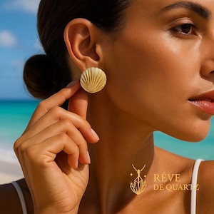 Peut inclure: Boucles d'oreilles rondes dorées avec un motif texturé en forme d'éventail. Les boucles d'oreilles sont portées sur l'oreille d'une personne. L'image comprend également le logo de la marque "Rêve de Quartz" en or.