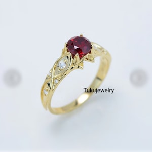 May include: A gold ring with a red gemstone and smaller white gemstones set in a floral design.