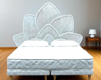 Könnte beinhalten: Ein weißes Bett mit einem einzigartigen Kopfteil. Das Kopfteil hat ein strukturiertes, blütenblattartiges Design. Das Bett hat eine weiße Matratze und zwei weiße Kissen. Der Bettrahmen ist hellgrau mit Holzbeinen. Der Raum hat eine neutrale Farbpalette.