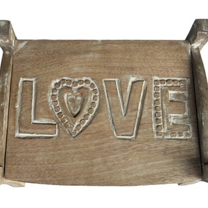 Pu&ograve; includere: Uno sgabello di legno con la parola "LOVE" intagliata nella parte superiore. Le lettere sono bianche e il cuore &egrave; decorato con un motivo intagliato.