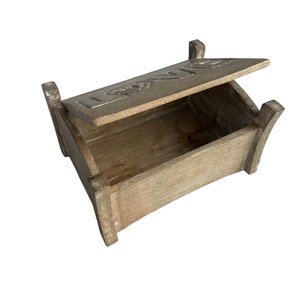 Pu&ograve; includere: Una scatola di legno con un coperchio incernierato. Il coperchio &egrave; aperto e la scatola &egrave; vuota. Il coperchio ha la parola "LOVE" incisa.