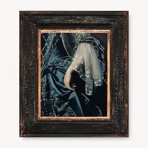 May include: A framed painting of a woman's hand and arm wearing a blue and white dress with lace detailing. The painting is in a dark wood frame with gold accents.
