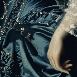 May include: A close-up of a blue satin dress with gold trim. The dress is gathered at the waist and has a ruffled hem. The fabric is soft and flowing.
