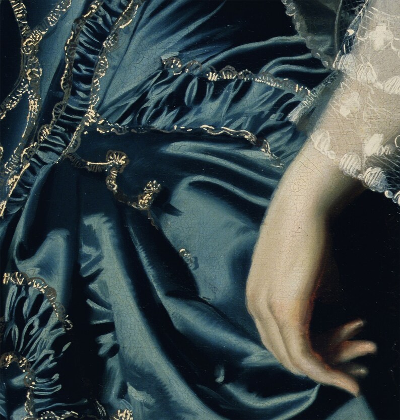 May include: A close-up of a blue satin dress with gold trim. The dress is gathered at the waist and has a ruffled hem. The fabric is soft and flowing.