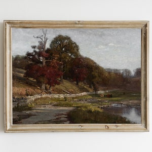 Può includere: Un dipinto ad olio incorniciato che rappresenta un paesaggio rurale con un ruscello, alberi e un muro di pietra. Gli alberi sono in tonalità di verde, marrone e rosso, e il cielo è di un azzurro chiaro con alcune nuvole. Ci sono alcune mucche nel campo.
