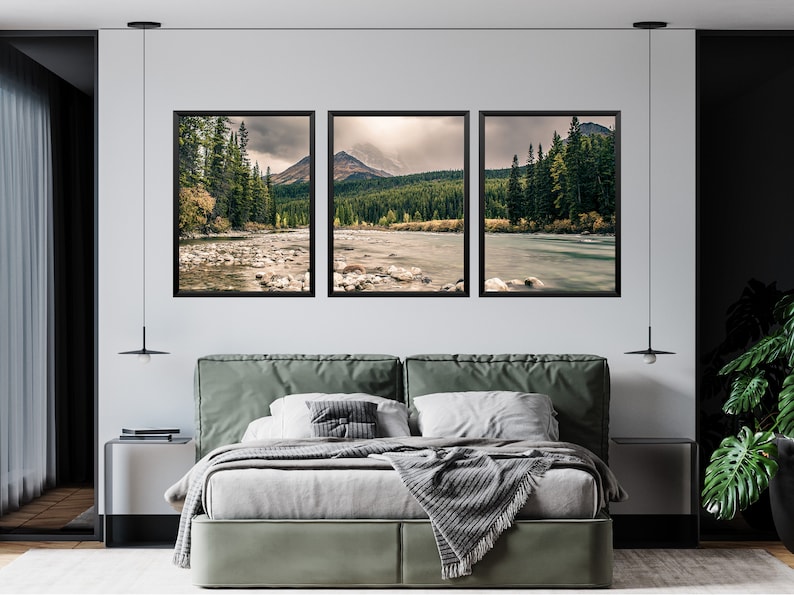 May include: Three framed landscape photographs of a river flowing through a forest with mountains in the background. The photos are hung on a white wall above a green upholstered bed.