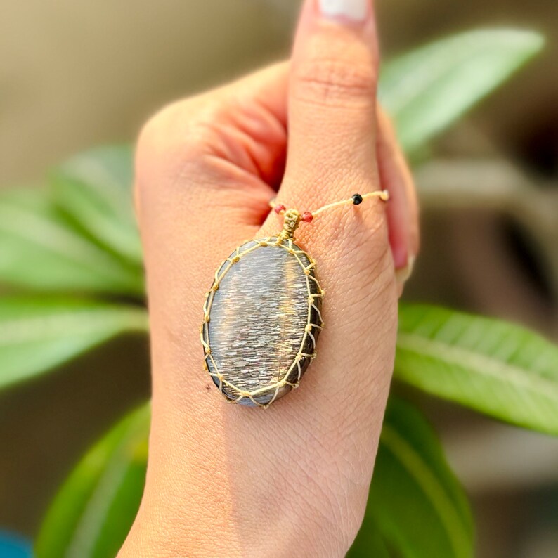 May include: A gold wire wrapped pendant featuring a large oval-shaped sunstone with a shimmering, iridescent finish.