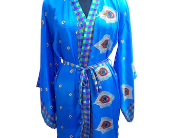Könnte beinhalten: Eine blaue Seidenrobe mit einem bunten Karomuster und einem Pfauenfeder-Druck. Die Robe hat einen Bindegürtel und lange Ärmel.