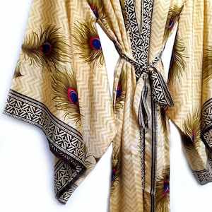 May include: A beige silk robe with a brown and white geometric pattern and peacock feathers. The robe has a tie belt and long sleeves.
