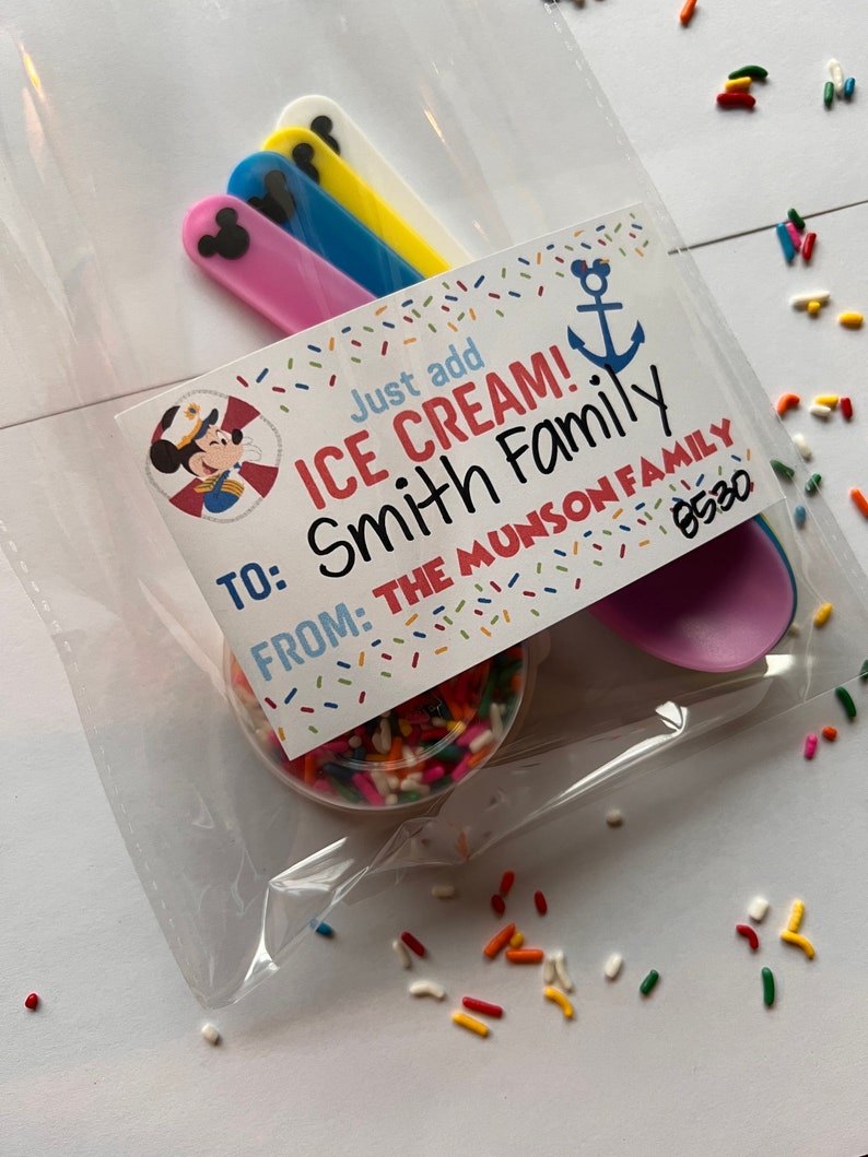 May include: A clear plastic bag filled with colorful sprinkles, four plastic spoons with Mickey Mouse ears, and a card that reads "Just add ICE CREAM! To: Smith Family From: The Munson Family 8530".