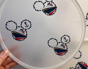 May include: Four white round hand fans with a blue and red ship design in the center. The ship is surrounded by a rope design in the shape of Mickey Mouse's head. Each fan has an anchor symbol above the ship.