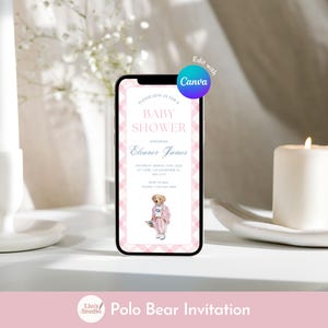 May include: A smartphone displays a baby shower invitation with a pink and white checkered border. The invitation features text, including the name Eleanor James and a Polo Bear illustration. A lit candle and a white candle holder are in the background.