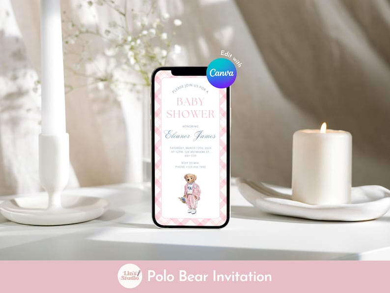 May include: A smartphone displays a baby shower invitation with a pink and white checkered border. The invitation features text, including the name Eleanor James and a Polo Bear illustration. A lit candle and a white candle holder are in the background.