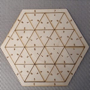 Può includere: Un puzzle esagonale in legno con i numeri da 1 a 9 stampati su ogni faccia. Il puzzle è progettato per essere risolto disponendo le facce in modo che i numeri su ogni lato si sommino allo stesso totale.