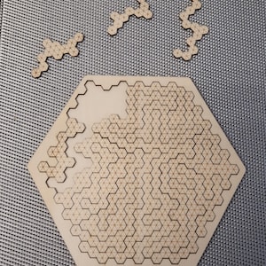 Può includere: Un puzzle esagonale in legno con un motivo a nido d'ape. Al puzzle mancano diversi pezzi, che sono mostrati separatamente.