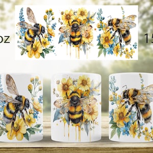 May include: Two white ceramic mugs with a bee and flower design. The mug on the left is 11 oz and the mug on the right is 15 oz.