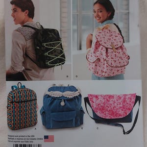 May include: Simplicity pattern 1388 for backpacks in one size. The envelope displays five variations: a camouflage bag with green cord, a pink floral backpack, a geometric print bag, a blue denim bag with wing accents, and a pink rose flap bag.