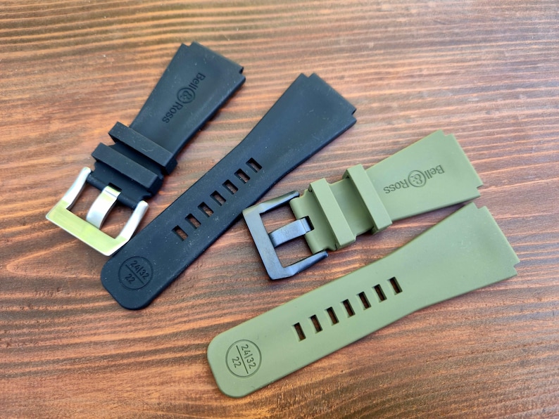 May include: Four watch straps in black and olive green, with silver and black buckles. The straps are made of a flexible material and feature the Bell & Ross logo. The straps are marked with the size 24/32 22.