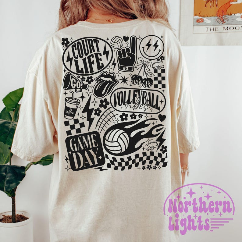 K&ouml;nnte beinhalten: Cremefarbenes T-Shirt mit einem schwarz-wei&szlig;en Volleyball-Motiv auf dem R&uuml;cken. Das Design enth&auml;lt die W&ouml;rter "Court Life", "Volleyball Vibes" und "Game Day" sowie Volleyballb&auml;lle und andere sportbezogene Symbole.