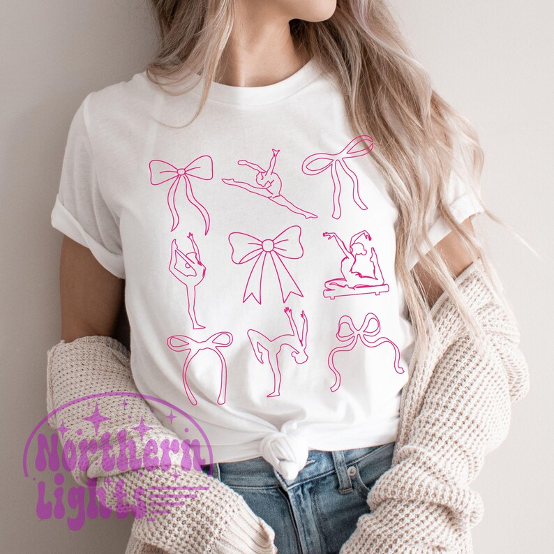 K&ouml;nnte beinhalten: Wei&szlig;es T-Shirt mit einem rosa Umrissdesign von Schleifen und Ballettposen. Das Shirt hat einen Rundhalsausschnitt und kurze &Auml;rmel. Der Text "Northern Lights" ist in lila Schrift unten links aufgedruckt.