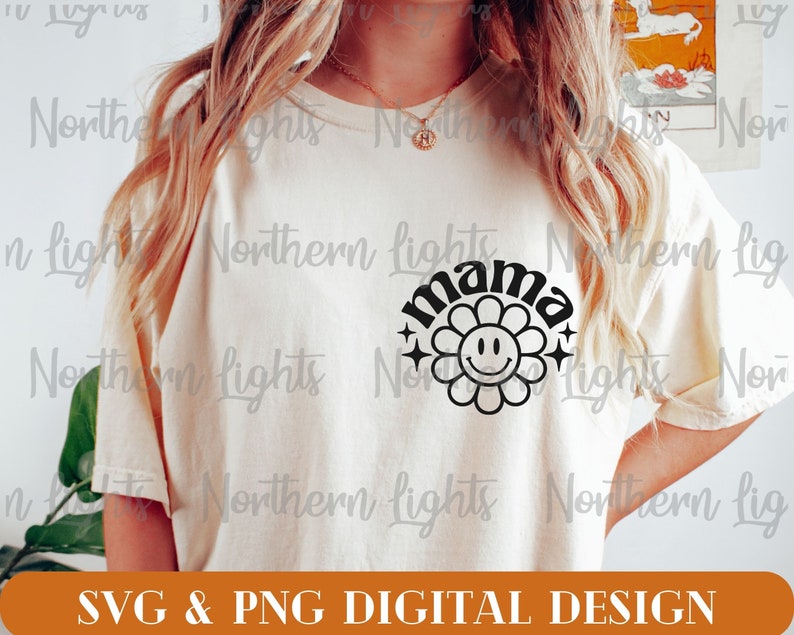 Op de afbeelding: Een wit T-shirt met een zwart grafisch ontwerp van een bloem met een smiley-gezicht en het woord "mama" in een retro-lettertype.