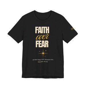 Pode incluir: Camiseta preta com as palavras "FAITH over FEAR" em uma fonte estilizada, com um gráfico de estrela abaixo. O texto "DO NOT FEAR, FOR I AM WITH YOU. ISAIAH 41:10" é impresso abaixo da estrela.
