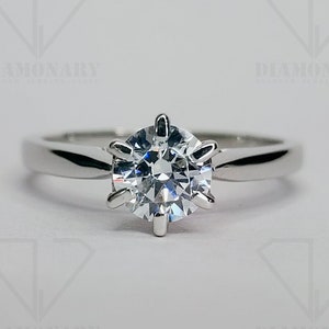 May include: A silver solitaire engagement ring with a round brilliant cut diamond.