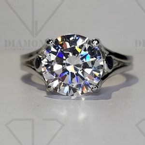 May include: A silver ring with a large, round, clear center stone and two smaller, round, dark blue stones on either side of the center stone.