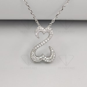 May include: A silver necklace with a pendant shaped like two interlocking hearts. The pendant is covered in small, clear cubic zirconia stones.