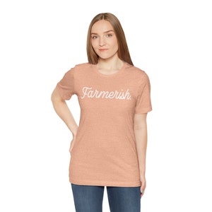 May include: A peach-colored t-shirt with the text "Farmerish" in white cursive lettering.
