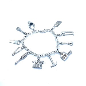 May include: A silver charm bracelet with various tool charms, including a saw, screwdriver, wrench, hammer, paintbrush, and a toolbox charm with the text "25" on it.