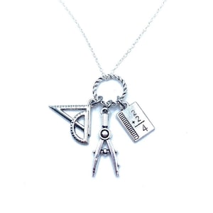 May include: Silver necklace with a charm of a compass, protractor, and a notebook with the equation 2/4 * 2.