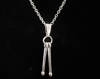 May include: A silver necklace with a pendant shaped like a pair of drumsticks.