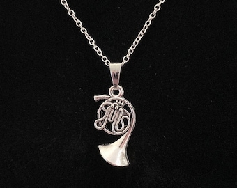 May include: A silver chain necklace with a silver french horn pendant. The horn is detailed with a winding design and a small bell.
