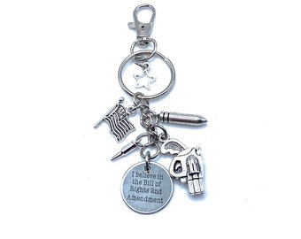 May include: Silver keychain with a star, American flag, bullet, gun, and a round charm that says "I believe in the Bill of Rights 2nd Amendment".