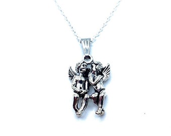 May include: Silver necklace with a pendant of two angels kissing. The angels are depicted in a romantic embrace, with their wings spread out behind them.