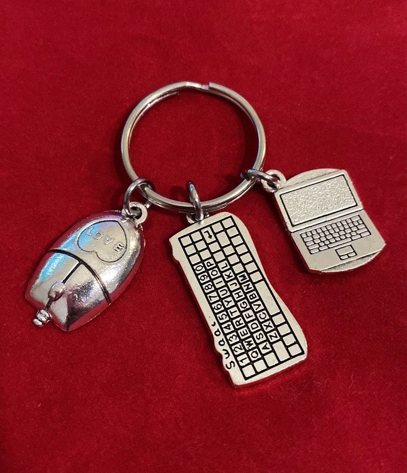May include: A silver keychain with three charms: a computer mouse with a heart that says "Love", a keyboard with the letters "SWQ...Z", and a laptop with a blank screen.
