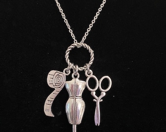 May include: Silver necklace with a silver charm of a dress form, a pair of scissors, and a measuring tape.