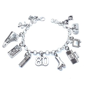 May include: A silver-toned charm bracelet featuring various miniature pendants including a high-top sneaker, a cassette tape, a hairspray can labeled "HAIR SPRAY," the number "80," a roller skate, a boombox, a television, a ghost figure, and glasses.